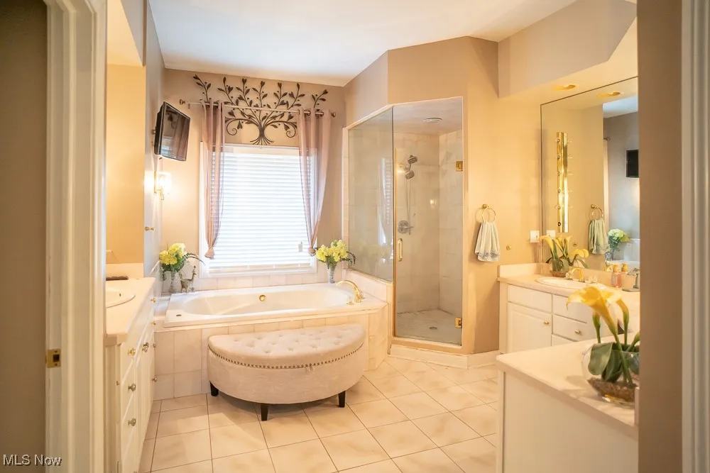 Bathroom with vanity, a shower stall, light tile patterned flooring, and a garden tub