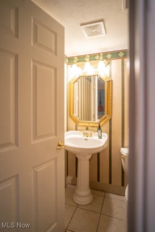 Bathroom with light tile patterned flooring and a textured ceiling