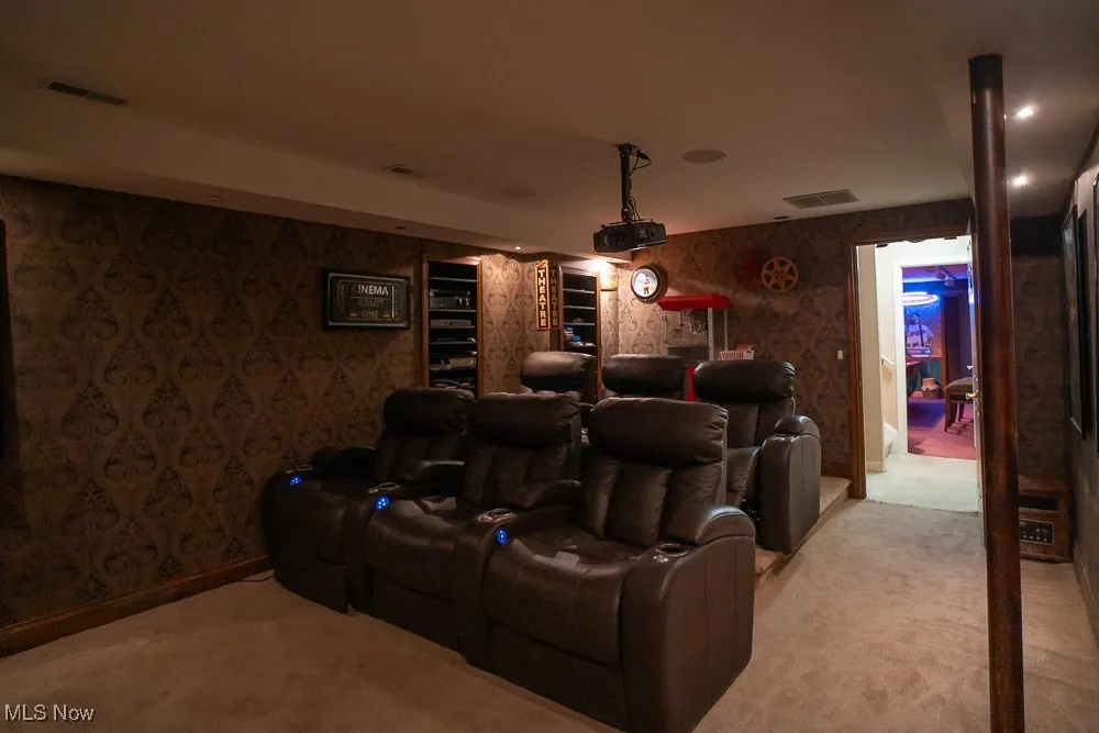 Home theater room featuring wallpapered walls and light colored carpet