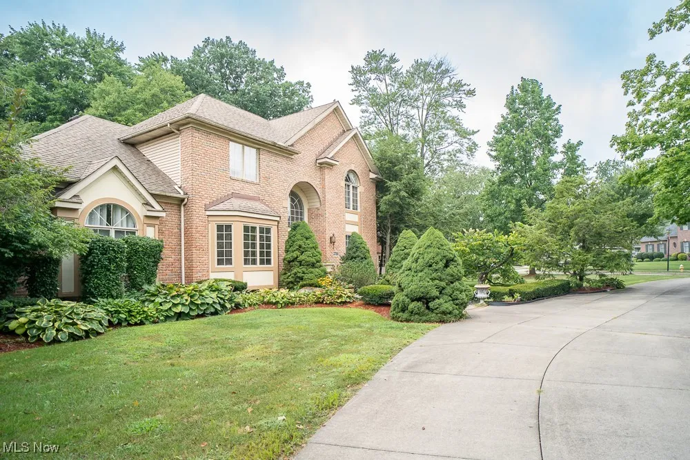 View of front of house featuring a front lawn, brick siding, and roof with shingles