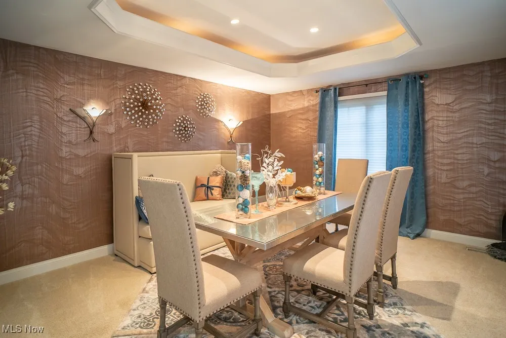 Dining room featuring a tray ceiling, light colored carpet, wallpapered walls, and recessed lighting