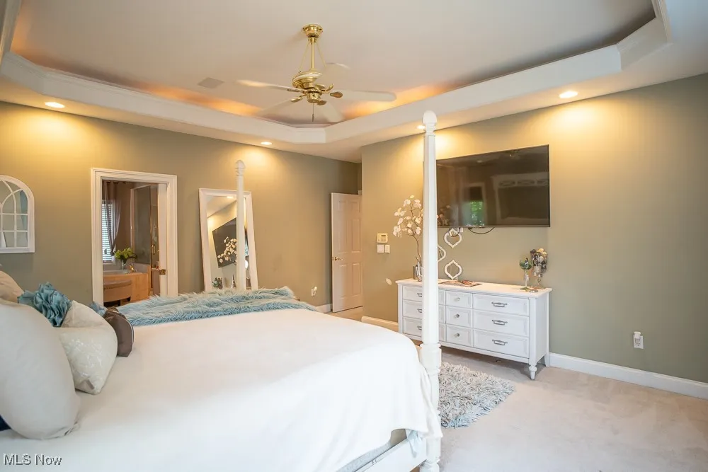 Bedroom featuring a tray ceiling, light carpet, recessed lighting, ceiling fan, and ornamental molding