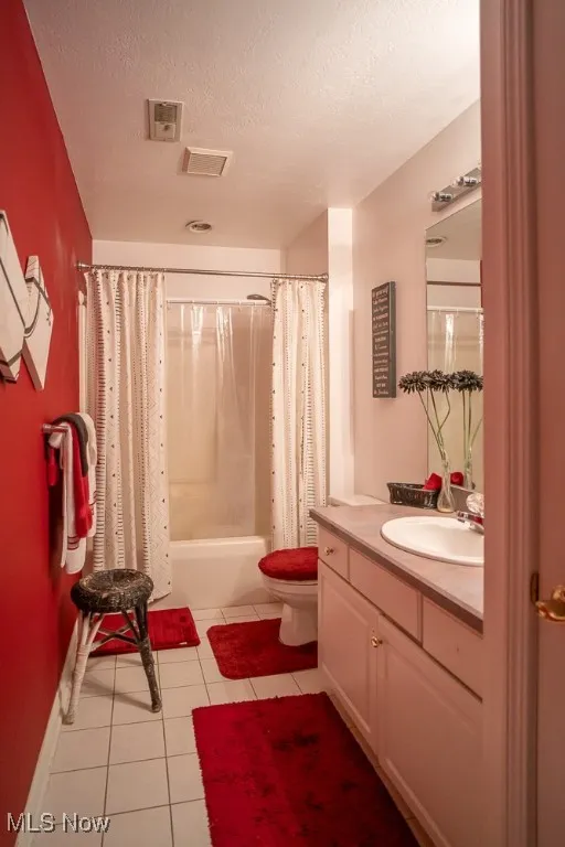 Full bath with a textured ceiling, shower / bathtub combination with curtain, light tile patterned floors, and vanity