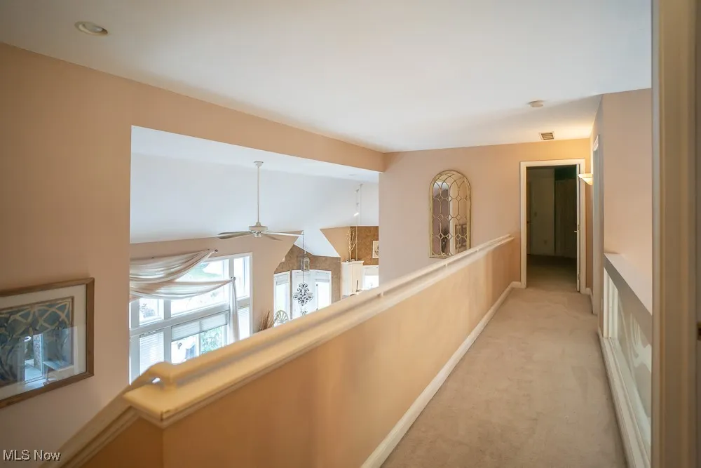 Hallway with carpet and vaulted ceiling
