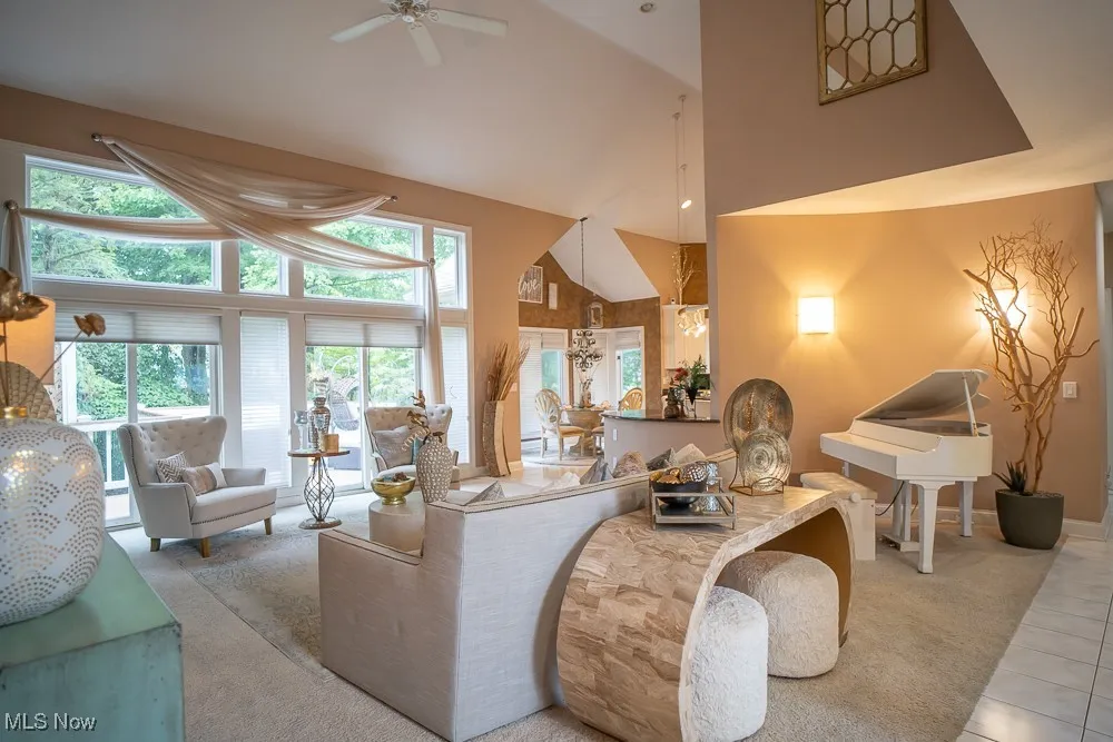 Carpeted living room with high vaulted ceiling, tile patterned floors, recessed lighting, and a ceiling fan