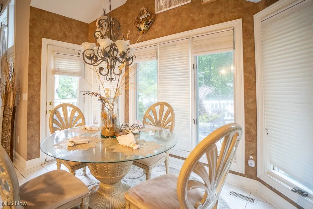 Tiled dining area featuring wallpapered walls and a chandelier