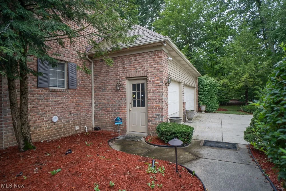 Property entrance with concrete driveway, brick siding, and a garage