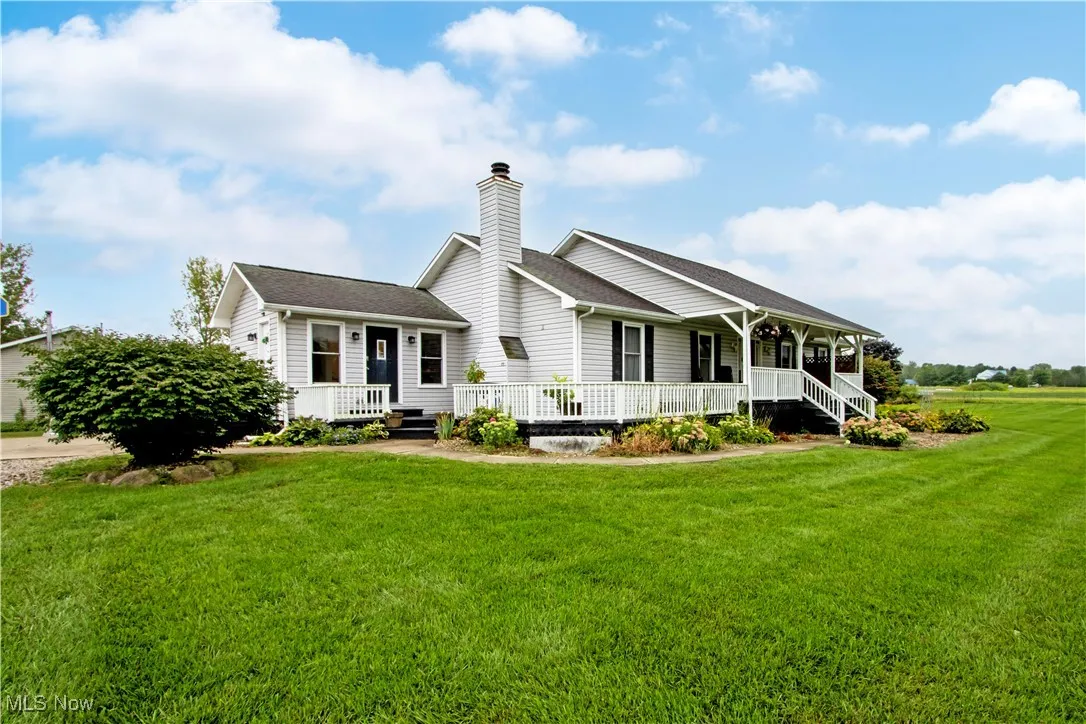 Back of property with covered porch, a lawn, a chimney, and roof with shingles
