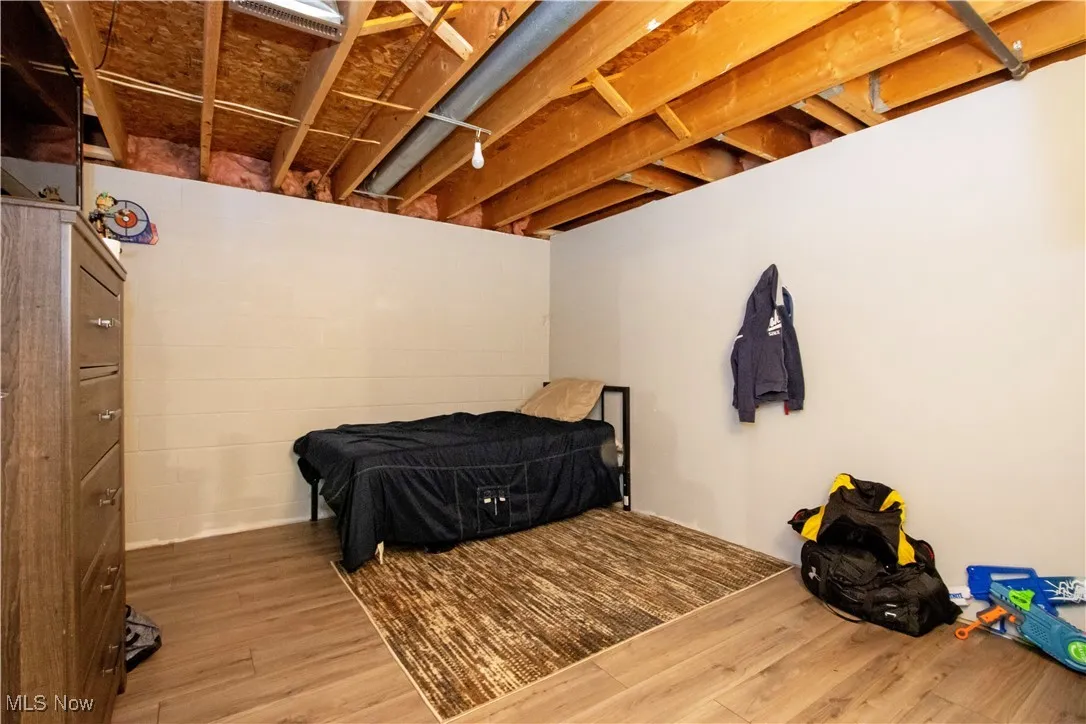 Bedroom featuring wood finished floors and concrete block wall