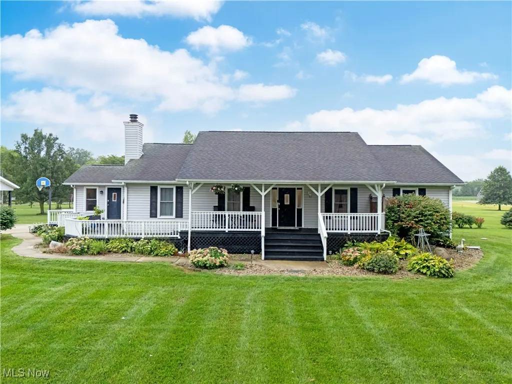 View of front of home with a porch, a front lawn, a chimney, and roof with shingles