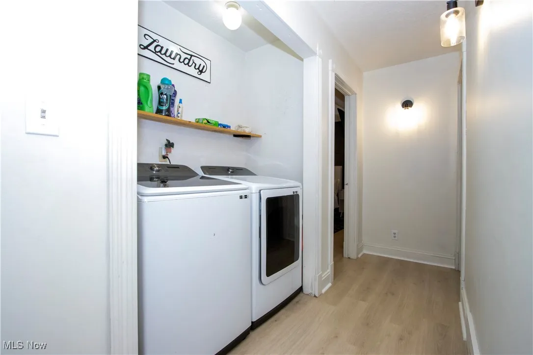 Washroom featuring light wood finished floors and washing machine and clothes dryer