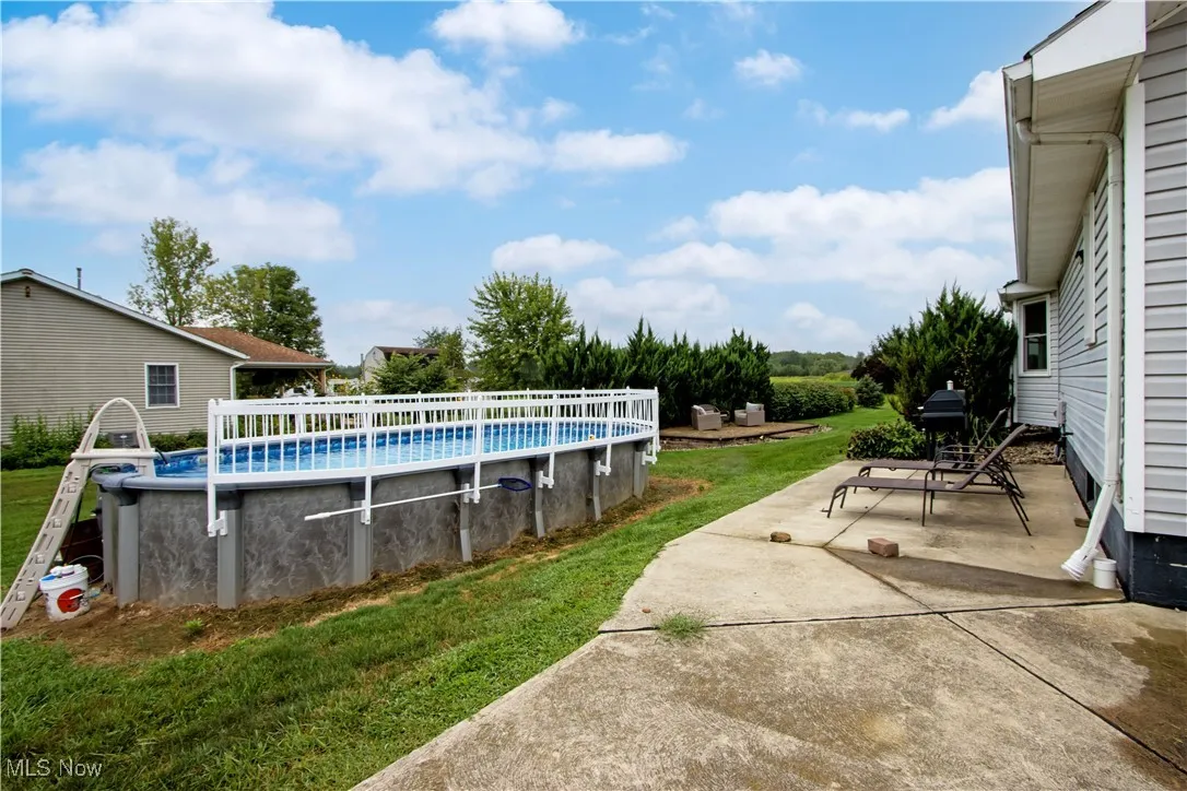 Swimming pool with a patio and a yard