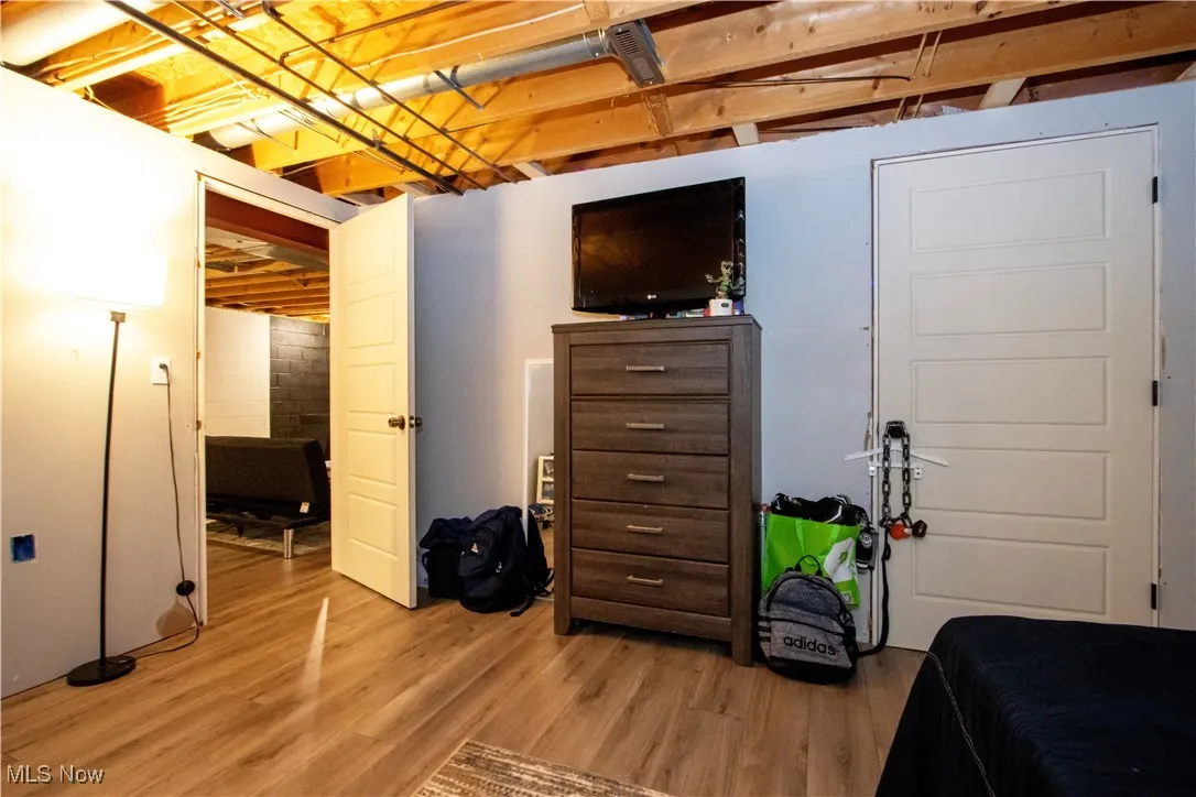 Bedroom with wood finished floors and concrete block wall