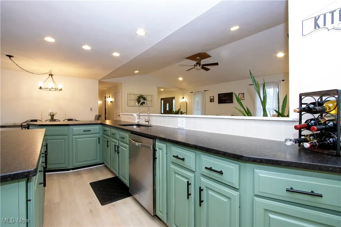 Kitchen with light wood-style floors, lofted ceiling, stainless steel dishwasher, green cabinetry, and recessed lighting