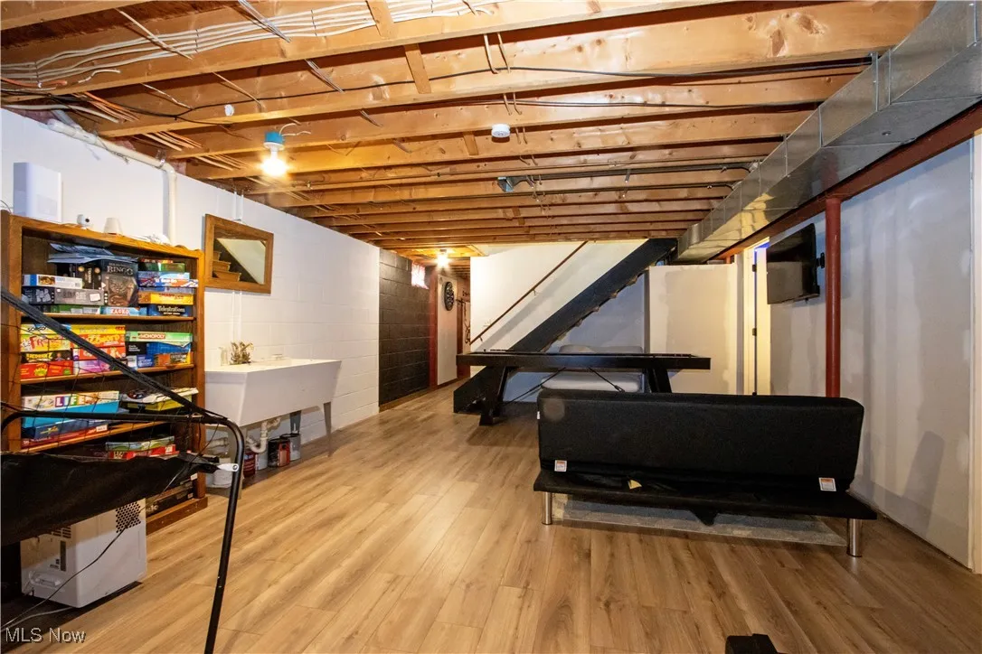 Unfinished basement featuring stairway and light wood-type flooring