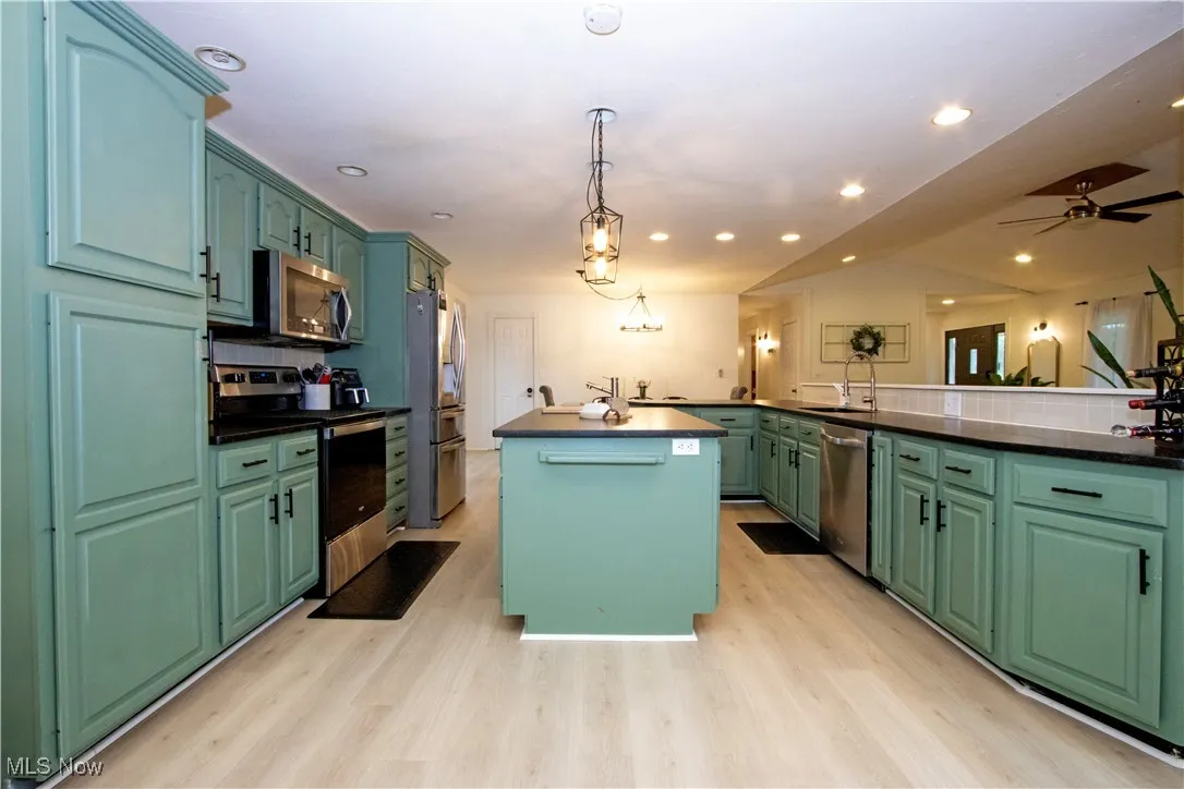 Kitchen with appliances with stainless steel finishes, a center island, green cabinets, tasteful backsplash, and recessed lighting