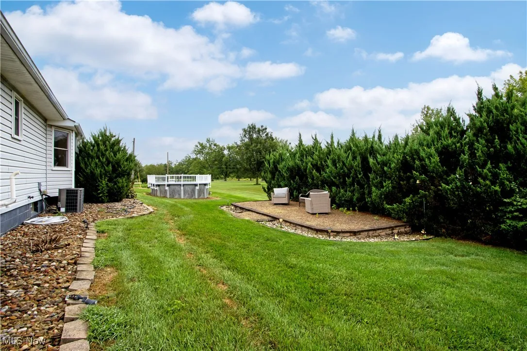 View of grassy yard featuring a patio and an outdoor pool