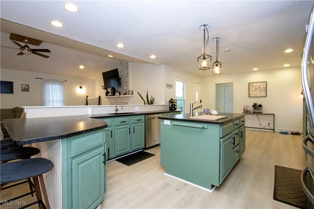 Kitchen with a breakfast bar area, light wood-style floors, recessed lighting, open floor plan, and pendant lighting