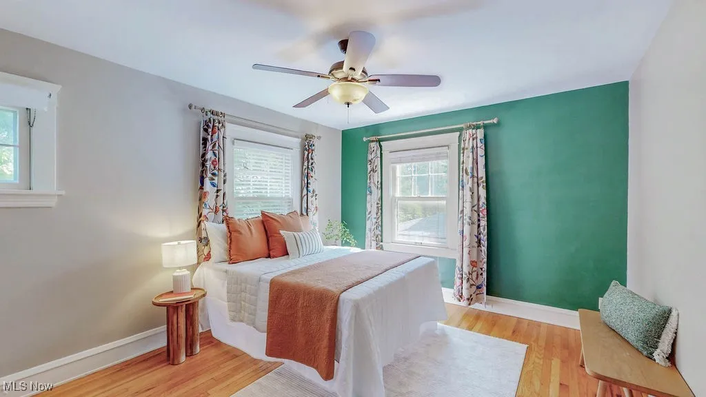 Primary bedroom with hardwood floors and ceiling fan.