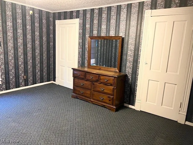 Bedroom featuring dark carpet and wallpapered walls