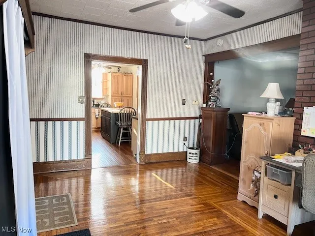 Office area featuring dark wood-style flooring, wallpapered walls, and crown molding