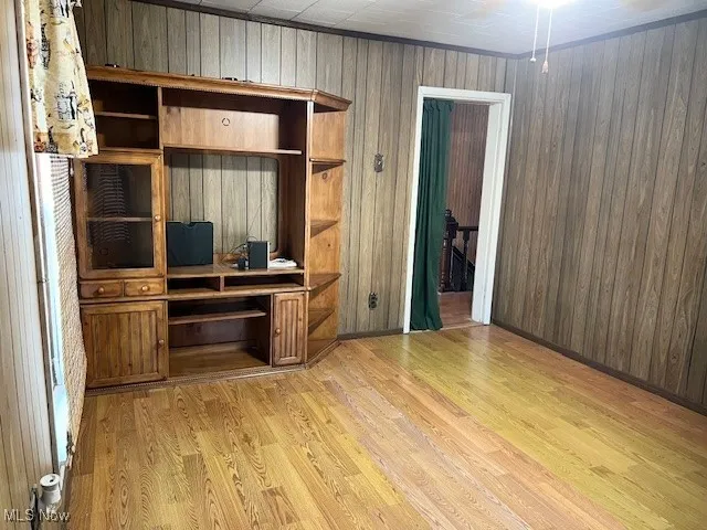 Unfurnished office /bedroom featuring light wood-type flooring and wooden walls