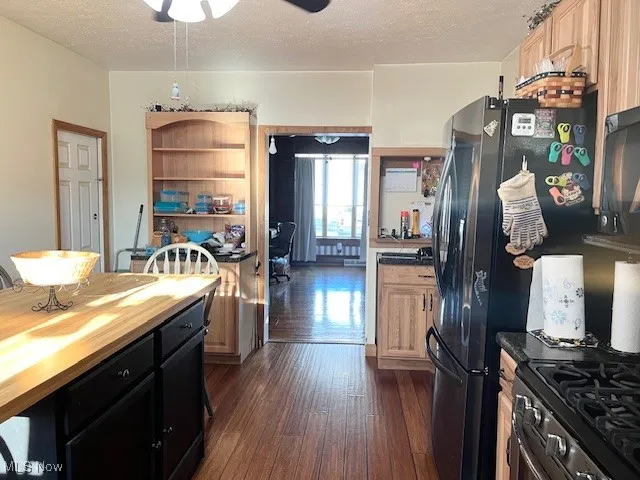 Kitchen featuring dark cabinetry, a textured ceiling, dark wood finished floors, ceiling fan, and butcher block counters
