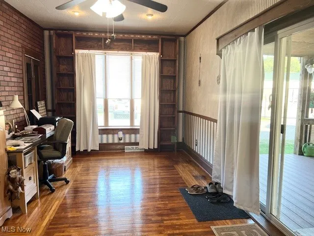 Office featuring built in features, wood finished floors, brick wall, and a ceiling fan
