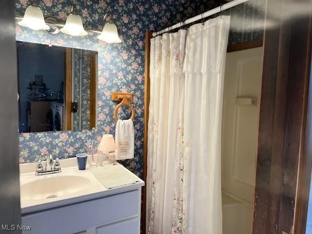 Bathroom with vanity and wallpapered walls
