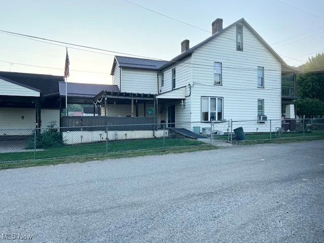 View of front facade featuring a fenced front yard, a chimney, and a gate