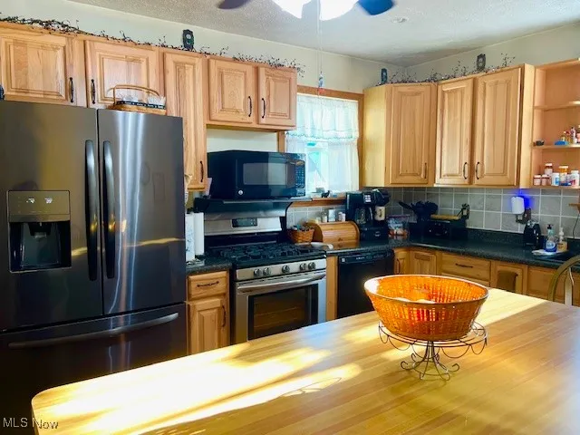 Kitchen with black appliances, dark countertops, tasteful backsplash, a ceiling fan, and open shelves