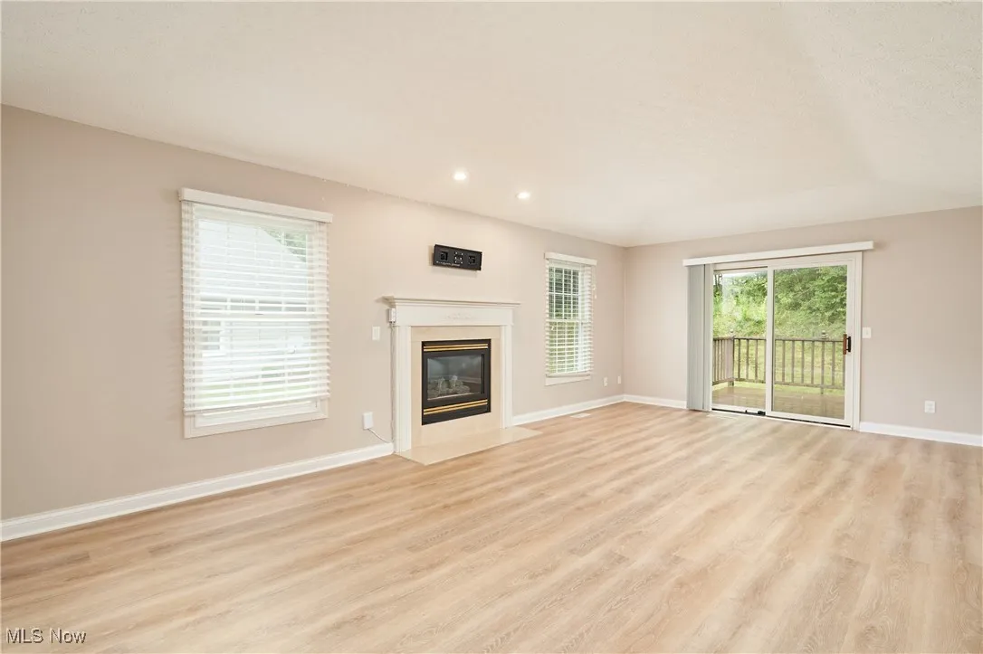 large living room with gas fireplace and sliding door leading to deck