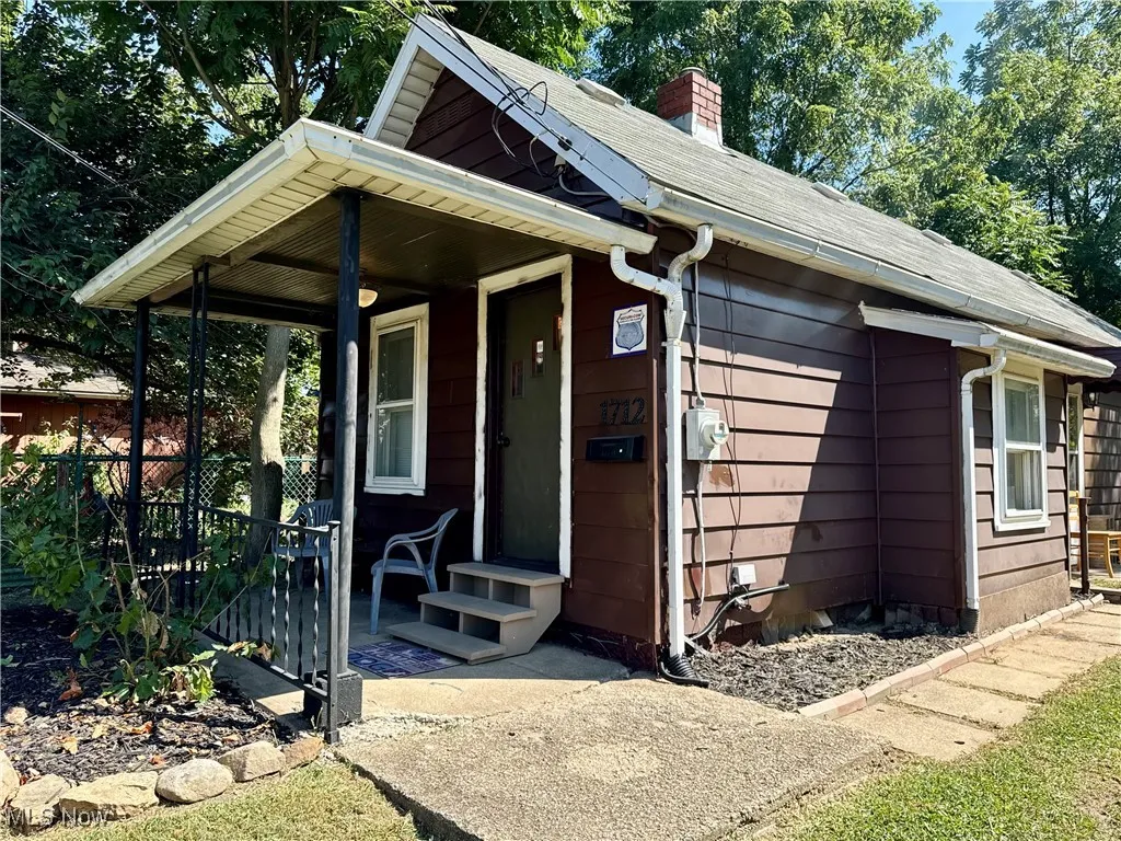 Bungalow featuring a chimney and a porch