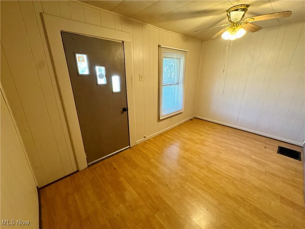 Entryway with wood walls, light wood-style flooring, and a ceiling fan
