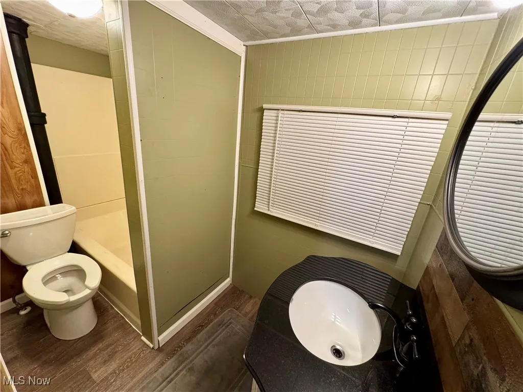 Full bath with dark wood-style flooring, crown molding, and vanity