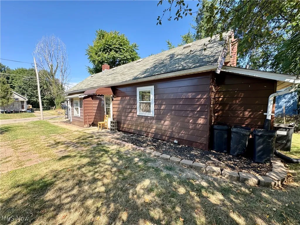 View of side of home featuring a chimney and a yard