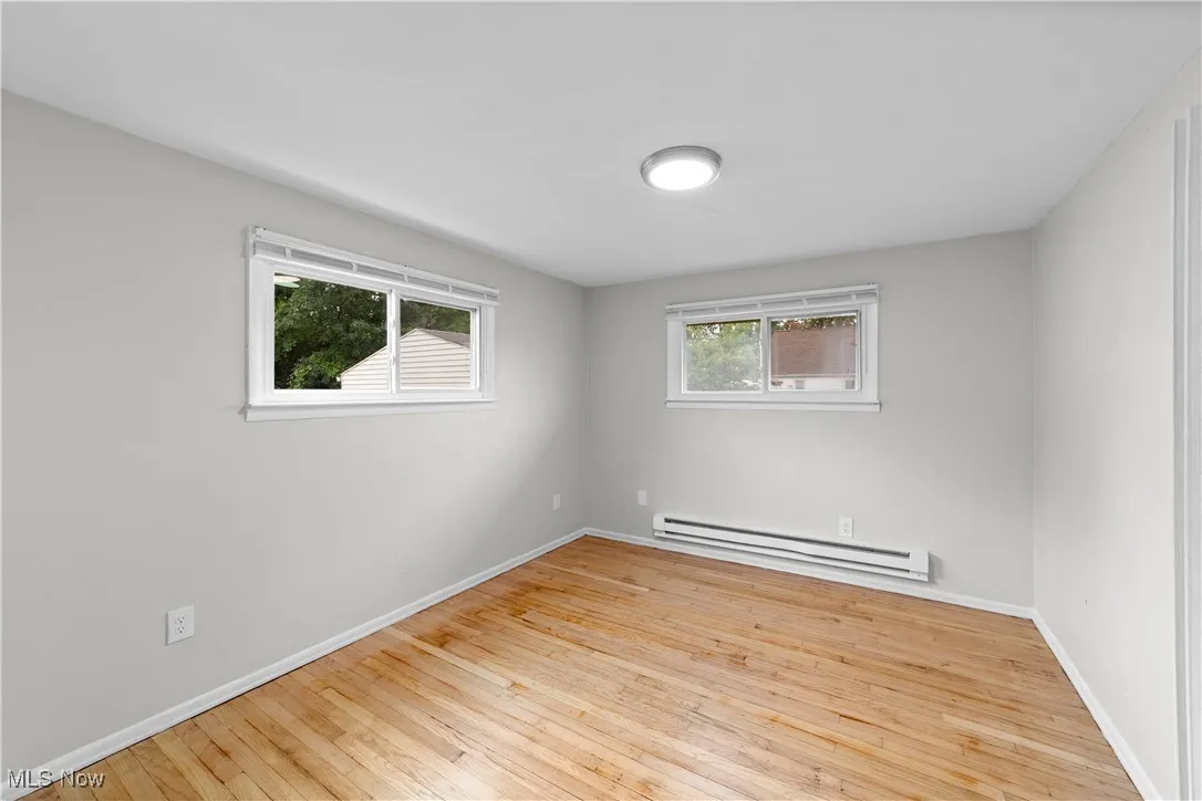 Spare room featuring light wood-style flooring, a baseboard heating unit, and plenty of natural light
