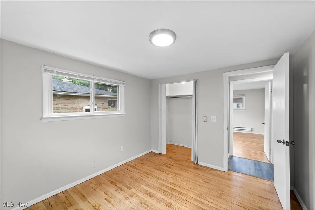 Unfurnished bedroom featuring light wood-style flooring, a closet, and a baseboard heating unit