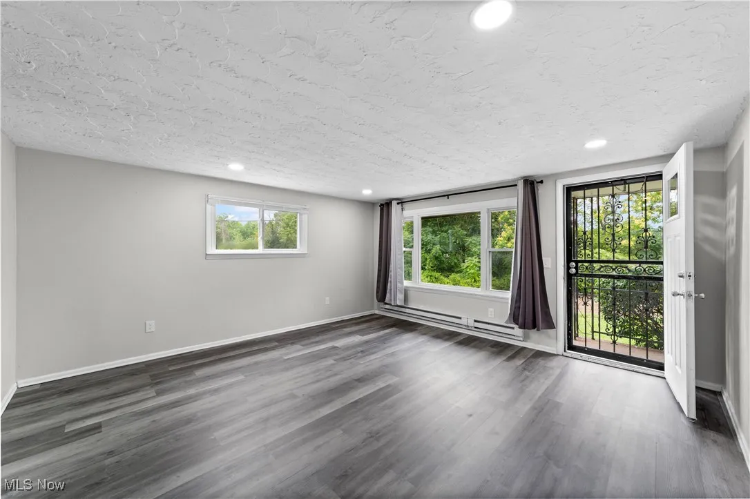 Unfurnished room with dark wood finished floors, recessed lighting, a baseboard heating unit, and a textured ceiling