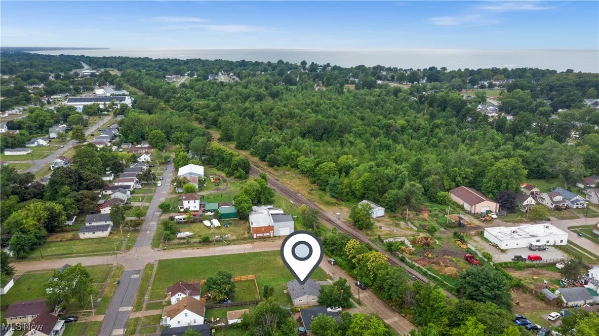 Aerial view of property and surrounding area featuring nearby suburban area and a large body of water