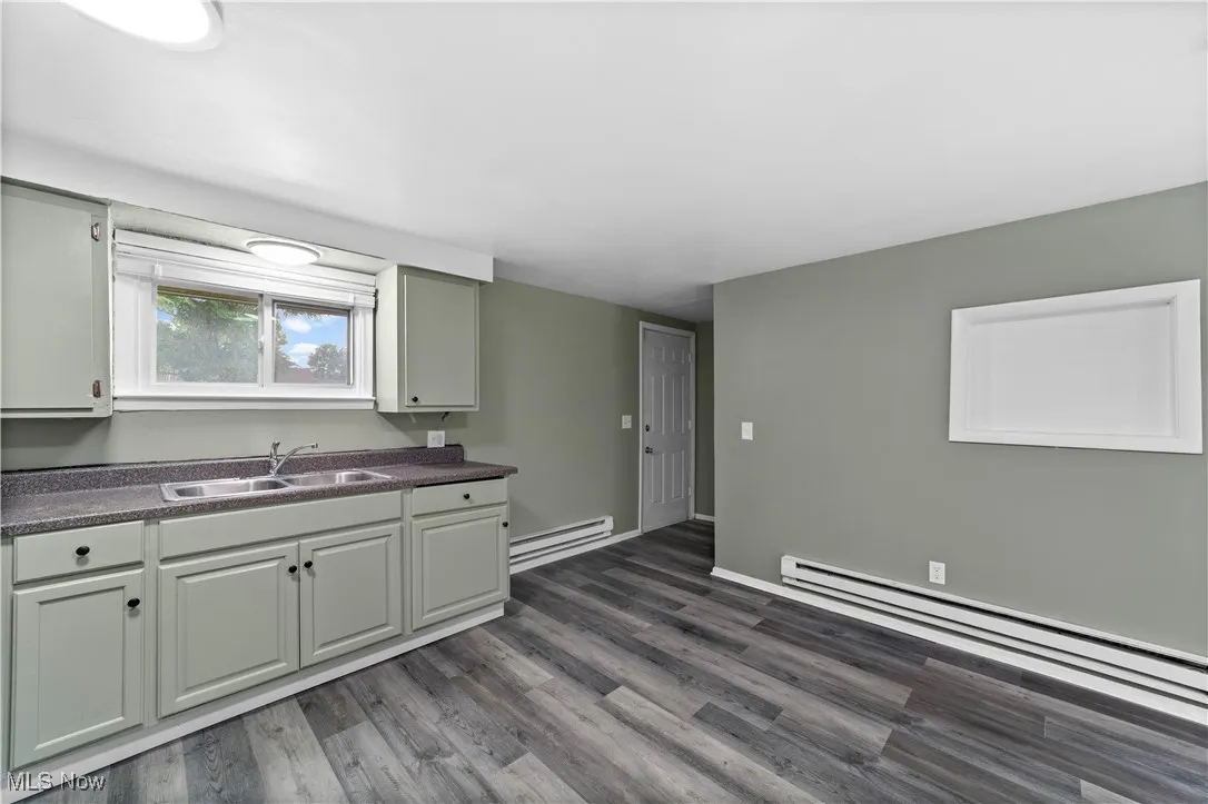 Kitchen with dark countertops, dark wood-style flooring, and a baseboard heating unit