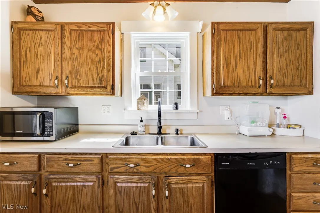 Kitchen featuring light countertops, dishwasher, stainless steel microwave, and brown cabinets
