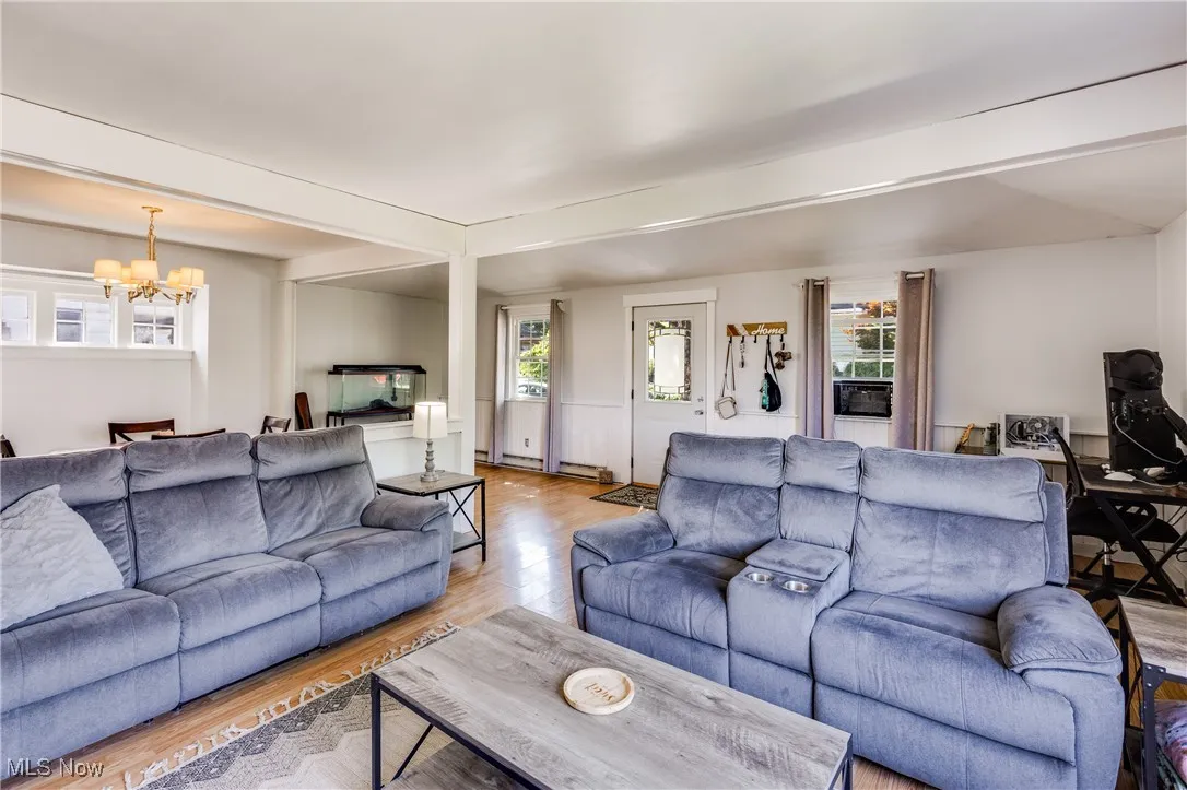 Living area featuring wood finished floors, healthy amount of natural light, a chandelier, and beam ceiling