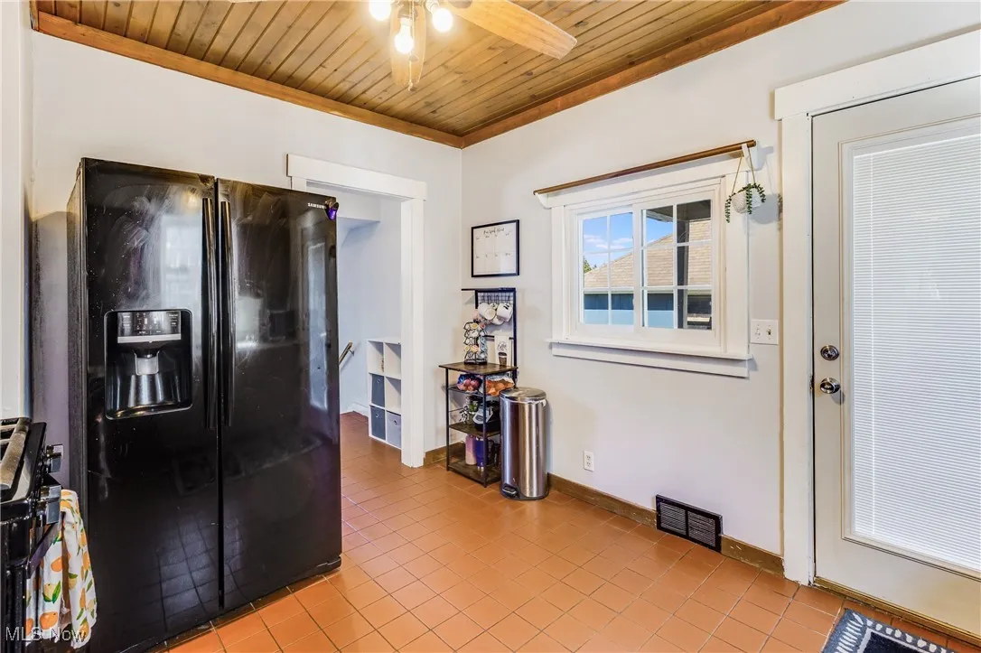 Kitchen featuring black appliances, light tile patterned floors, wooden ceiling, and ceiling fan