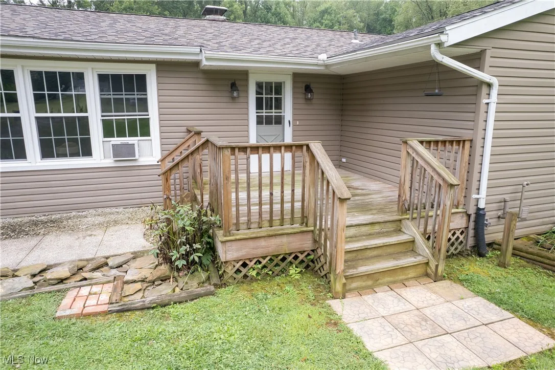 View of exterior entry with a shingled roof and a wooden deck