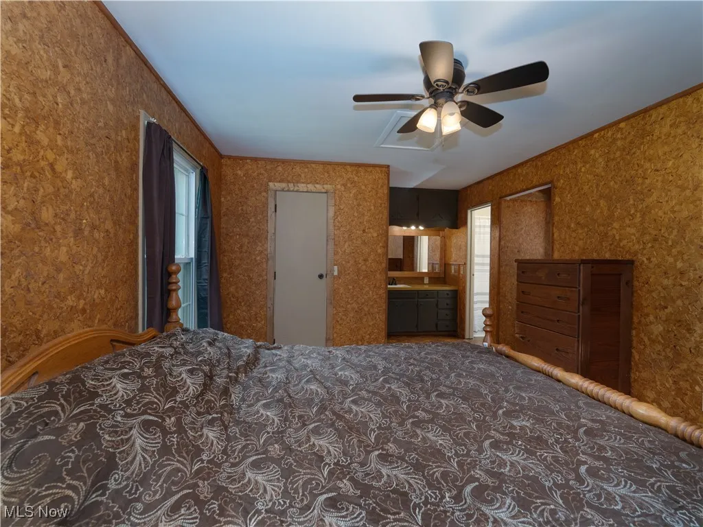 Carpeted bedroom with connected bathroom and ceiling fan