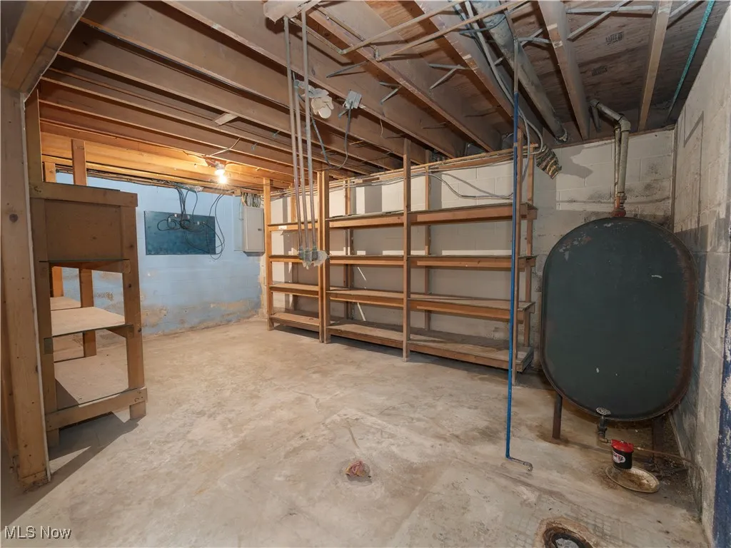 Unfinished below grade area featuring oil tank and electric panel