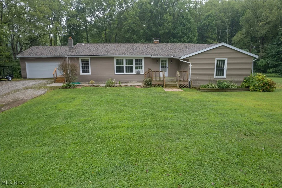 Ranch-style house with driveway, a garage, a chimney, and a front yard