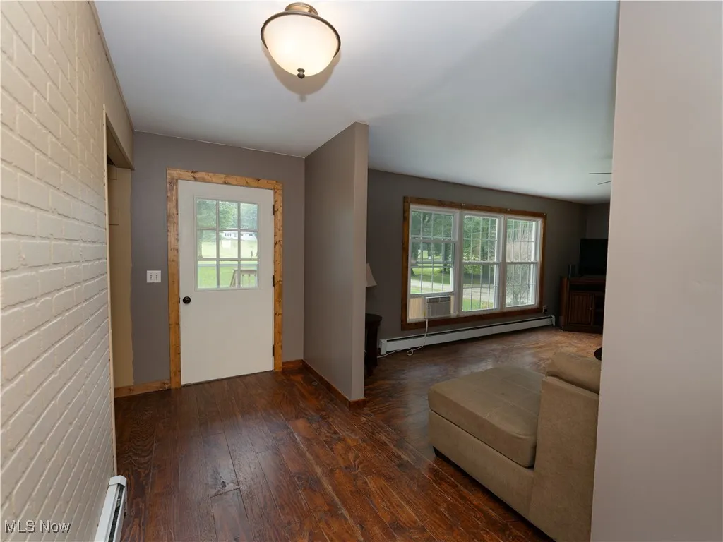Entryway featuring brick wall, baseboard heating, and hardwood / wood-style flooring