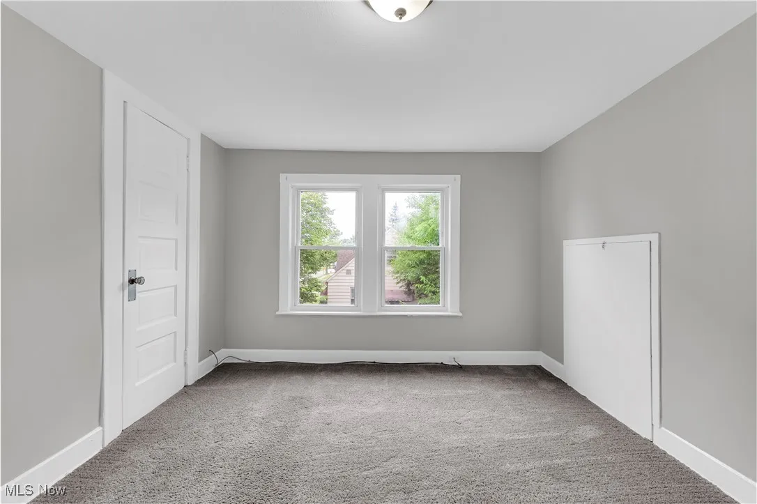 Spare room featuring light colored carpet and baseboards